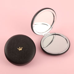 A 70* 70mm round PU leather bread mirror with small metal accessories and customizable patterns. It has a silver plated frame. The leather colors are available in black, red, khaki, and off-white pink.